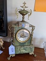 Front view of green marble clock showing gilt metal mounts, dial and paw feet