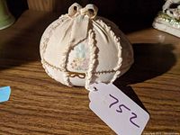 Front view showing fabric and floral porcelain panels with lace edges and ribbon bow on top