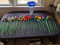 Wide view of vase and all 31 glass flowers laid out on table