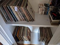 Shelves containing multiple stacks of vinyl records in paper sleeves