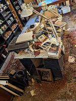Wooden island cluttered with books, two adjustable desk lamps, and other items, showing water damage and dirt on floor.