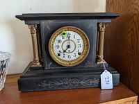 Frontal view of the Seth Thomas mantel clock showing four gold columns and decorative clock face with gold trim.