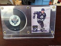 Signed Wendel Clark Toronto Maple Leafs hockey puck with portrait collectible card in clear display case on black base