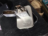 Close-up of Beatles Zippo lighter open showing interior metal and Beatles logo on front with Zippo branding