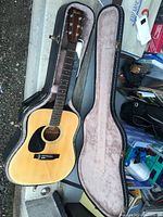 Left handed Fender acoustic guitar in open black hard shell case, showing the front of the guitar