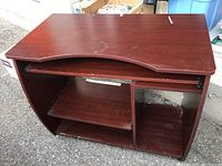 Front angle view of the wood-finish computer desk showing keyboard tray and side compartments.