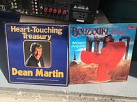 Two vinyl record album covers featuring Dean Martin's 'Heart-Touching Treasury' and Roberto Delgado's 'Bouzouki Vol. 2'.