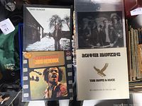 Four vinyl album covers featuring David Gilmour, Queen, Jimi Hendrix, and Ronnie Hawkins in plastic sleeves on display.