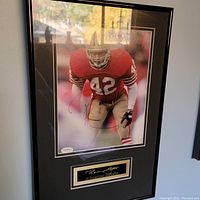 Full view of framed autographed photo of Ronnie Lott in red San Francisco 49ers jersey #42, with plaque below signature.