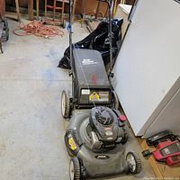 Full view of the Craftsman lawn mower showing the handle, wheels, engine, and grass collection bag.