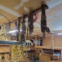 Metal chains hanging from wooden beam in workshop
