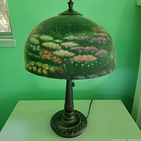 Photo of one lamp showing dome-shaped glass shade with floral garden artwork, metal base with textured design, and pull chain.