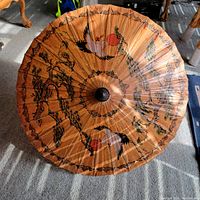 Top-down view of paper parasol showing entire design of cranes and bonsai trees with lacquered finish.