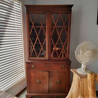 Front view of the Victorian style display cabinet showing the full height two-piece design with glass lattice doors on top and drawer with wooden doors below.