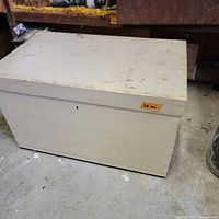 Closed white painted wooden chest with visible marks on top surface.