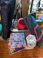 Photo showing bin with wrapped supplies, green/red storage bag, red basket, and some boxed items including the Noma power post set.
