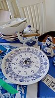 Ceramic Delft blue clock plate, teapot, and figurine displayed on a blue cloth