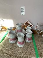 Photo showing all six cups turned upside down in a group with saucers stacked nearby, displaying pink patterns and general shape.