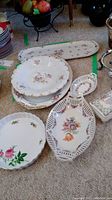 Overview of porcelain dishes and platters with floral patterns and gold accents