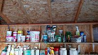Shelf with partial bottles of garden fertilizers and plant food including CIL, Miracle-Gro, Scott's, and Grub Away products
