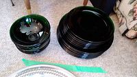 Overview of the stacked green glass bowls and plates on carpeted floor.