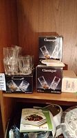 Photo showing 4 old fashioned glasses stacked, 12 hi-ball glasses stacked, two Classique Bohemia branded boxes, and coasters on top of the boxes