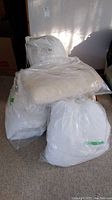 Four bedding items packaged in clear and white plastic bags; includes a silk duvet labeled bag, mattress cover, blanket, and down comforter.