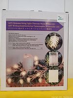 Box showing product details listing 16FT Pinecone shaped Christmas string lights with warm white LED, battery powered. Box includes text in multiple languages and photo examples of the string lights lit and unlit showing pinecone cover shape.
