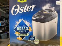 Oster ExpressBake Bread Maker in its original box showing front panel and branding.