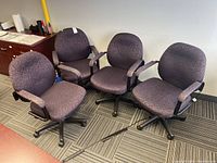 Four matching office chairs arranged in a corner, showing overall condition and upholstery color/pattern.