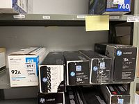 Five boxes of HP LaserJet toner cartridges on a shelf, labeled with models 92A, 304A, 35A, 12A, and 15A
