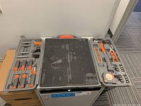Plastic toolbox open, showing organized tools inside including screwdrivers, hex keys, hammer, pliers, tape measure, spirit level, and bits.