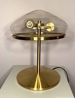 Front view showing brass base and clear glass shade with visible bulb inside.