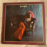 Front cover of Janis Joplin Pearl vinyl LP album showing the iconic image of Janis sitting on a chair.