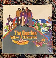 Front cover of The Beatles Yellow Submarine LP with colorful psychedelic illustration and band members standing on hill above yellow submarine.