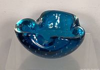 Front angle of deep blue vintage art glass ashtray showing bubble pattern and glossy finish.