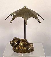 Front view of brass frog reclining and holding umbrella