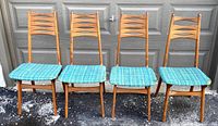 Front view of all four chairs showing blue-green upholstered seats and bow tie slatted backrests