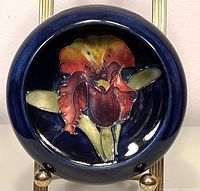 Top view showing detailed orchid pattern inside the bowl against a dark blue background.
