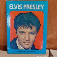 Front cover of 'The Life and Death of Elvis Presley' book with colored portrait surrounded by blue and orange borders.