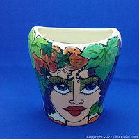 Front view of the ceramic planter showing the hand-painted female face with fruit and leaves design.