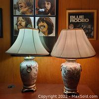 Pair of ceramic Asian lamps on wooden surface with different colored bulbs turned on, showing their elegant appearance and shades.