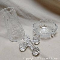 Three crystal clear glass items: etched vase, candy bowl, and faceted cutlery rest on cloth background.