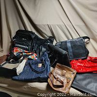 Photo of 9 purses of various colors and styles piled together showing black, red patent, brown, blue fabric, and beige accents