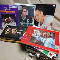 Photo showing close grouping of hockey-themed books including 'The Great Wingmen,' a hockey magazine with a player in a Kings jersey, a portrait of Gordie Howe, and the book 'Howe!'
