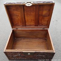 Open trunk showing the spacious wooden interior with visible grain and a solid wood hinged lid with metal clasp.