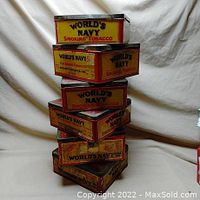 Stack of six old metal cigarette tobacco tins with yellow, red, and black branding 'World's Navy Smoking Tobacco.'