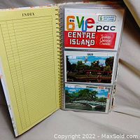 View of an open binder showing pockets with postcards inside and a yellow index page.