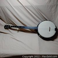 Full view of the vintage wooden banjo showing the neck, headstock, and drum head with missing strings.