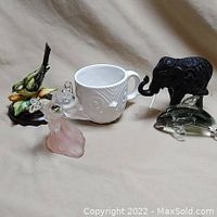 Photo showing all figurines together with the ceramic cup on beige background